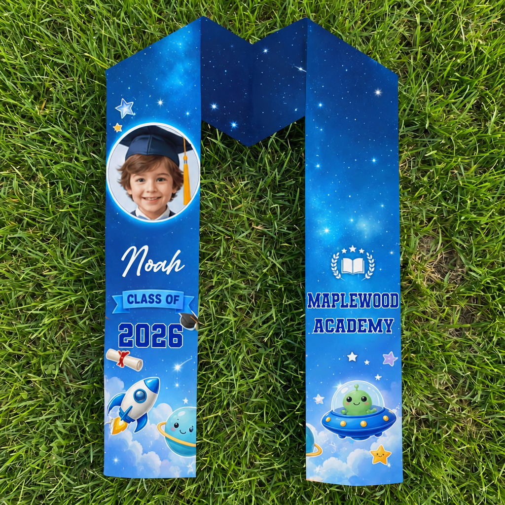 Blue galaxy rocket kid graduation stole with child photo, name Noah, Class of 2026 and Maplewood Academy laid flat on grass