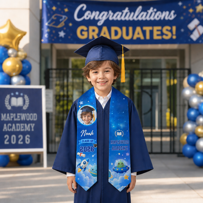 Boy in navy gown wearing the blue galaxy rocket photo stole reading Noah, Class of 2026 and Maplewood Academy