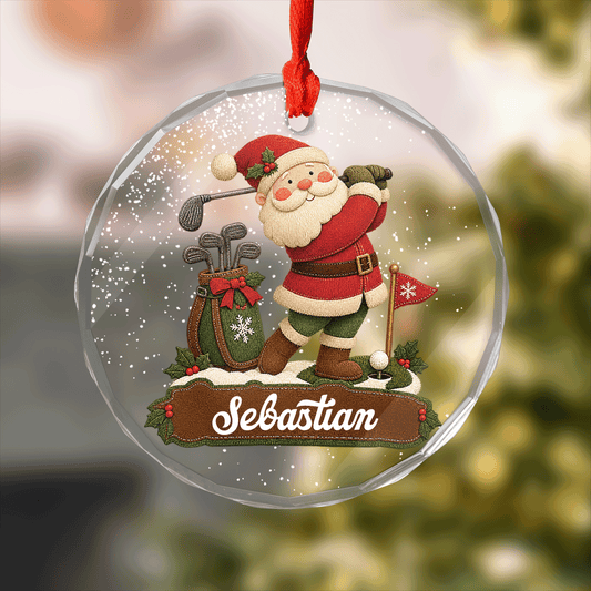 Round clear glass ornament with Santa swinging a golf club, golf bag, flag and a custom name banner