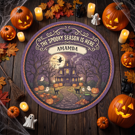 Personalized Halloween The Spooky Season Is Here Haunted House Round Rug with custom name, styled on a wood floor with pumpkins