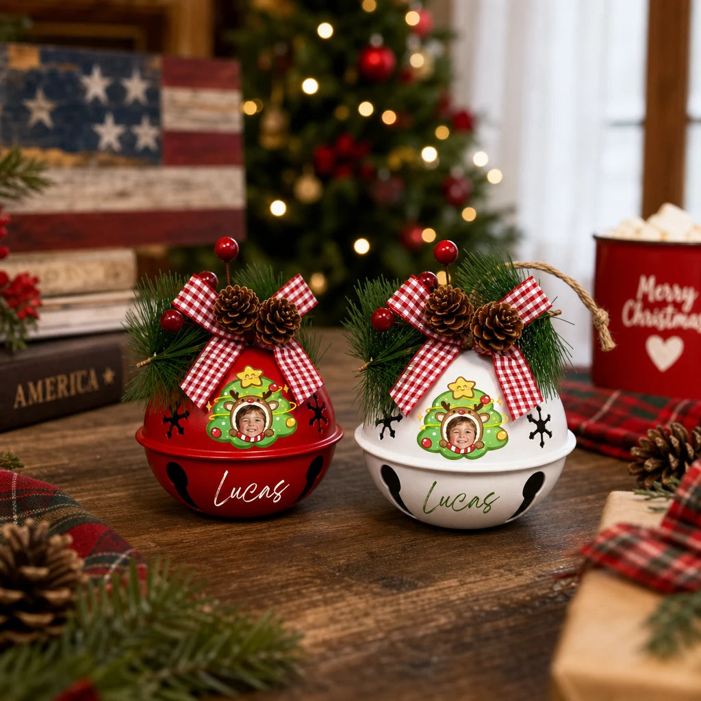 Two custom kid photo jingle bell ornaments displayed on a wooden table