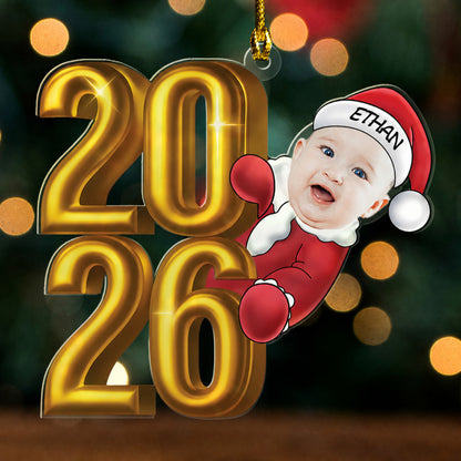 Acrylic ornament of gold 2026 numbers with a baby face in a Santa suit and a named Santa hat peeking out