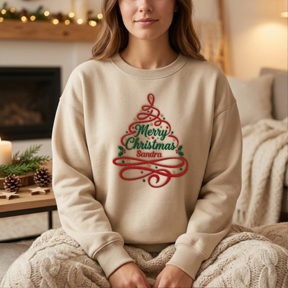 Woman wearing the sand Merry Christmas Ribbon Tree embroidered sweatshirt with custom name by a cozy fireplace