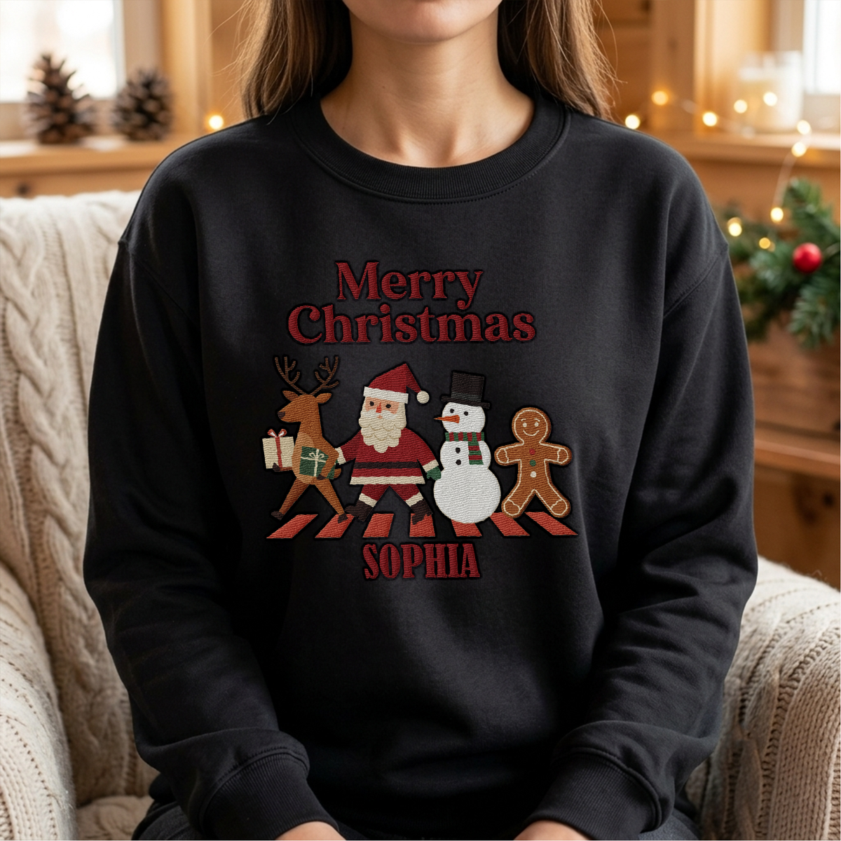 Woman wearing the black Merry Christmas Crew Crossing embroidered sweatshirt with custom name in a cozy living room