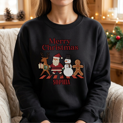 Woman wearing the black Merry Christmas Crew Crossing embroidered sweatshirt with custom name in a cozy living room