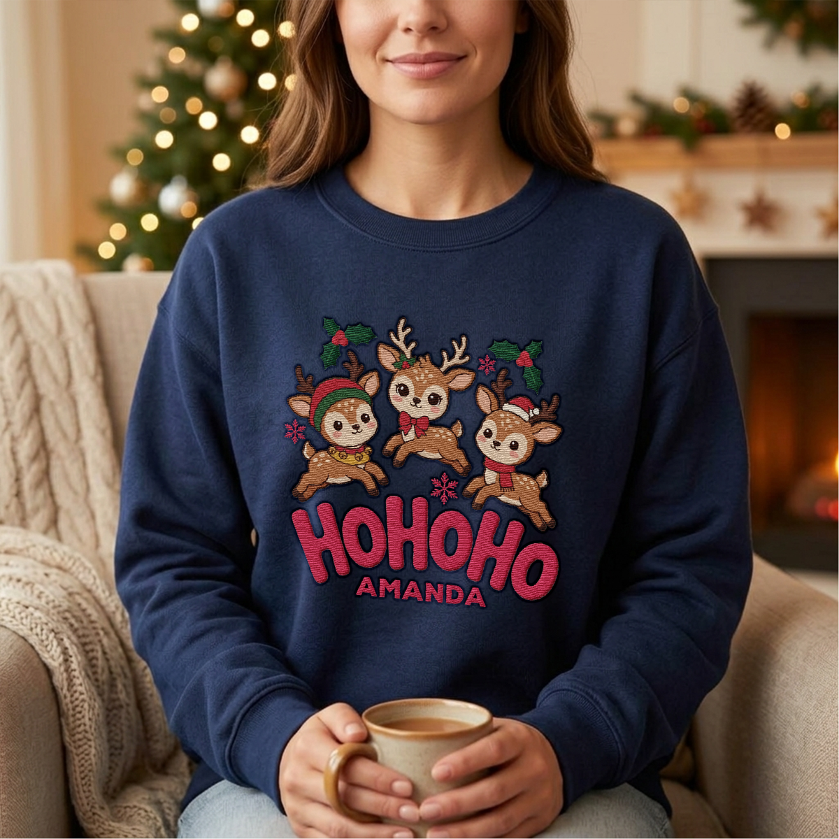 Woman wearing the navy Ho Ho Ho Baby Reindeer embroidered sweatshirt with custom name by a cozy fireplace
